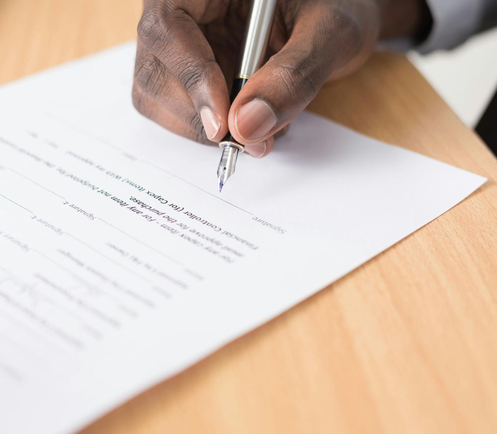 A hand signing a document with a fountain pen